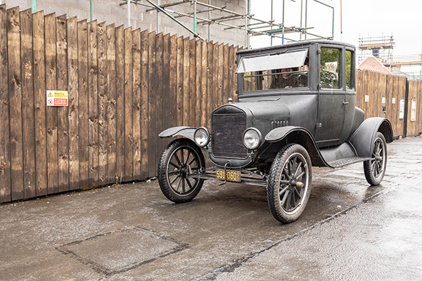 Old Model T car next to a fence